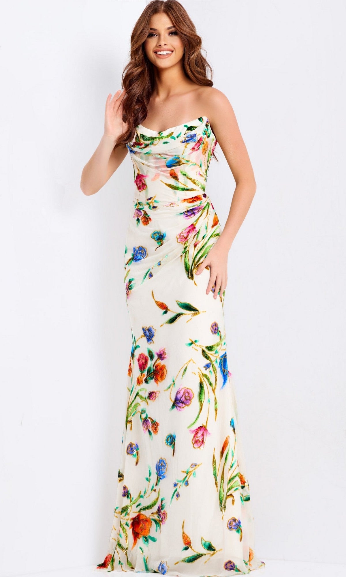 A woman smiles while wearing the Jovani 47626 long prom dress, featuring a colorful strapless floral print, standing against a plain white background.